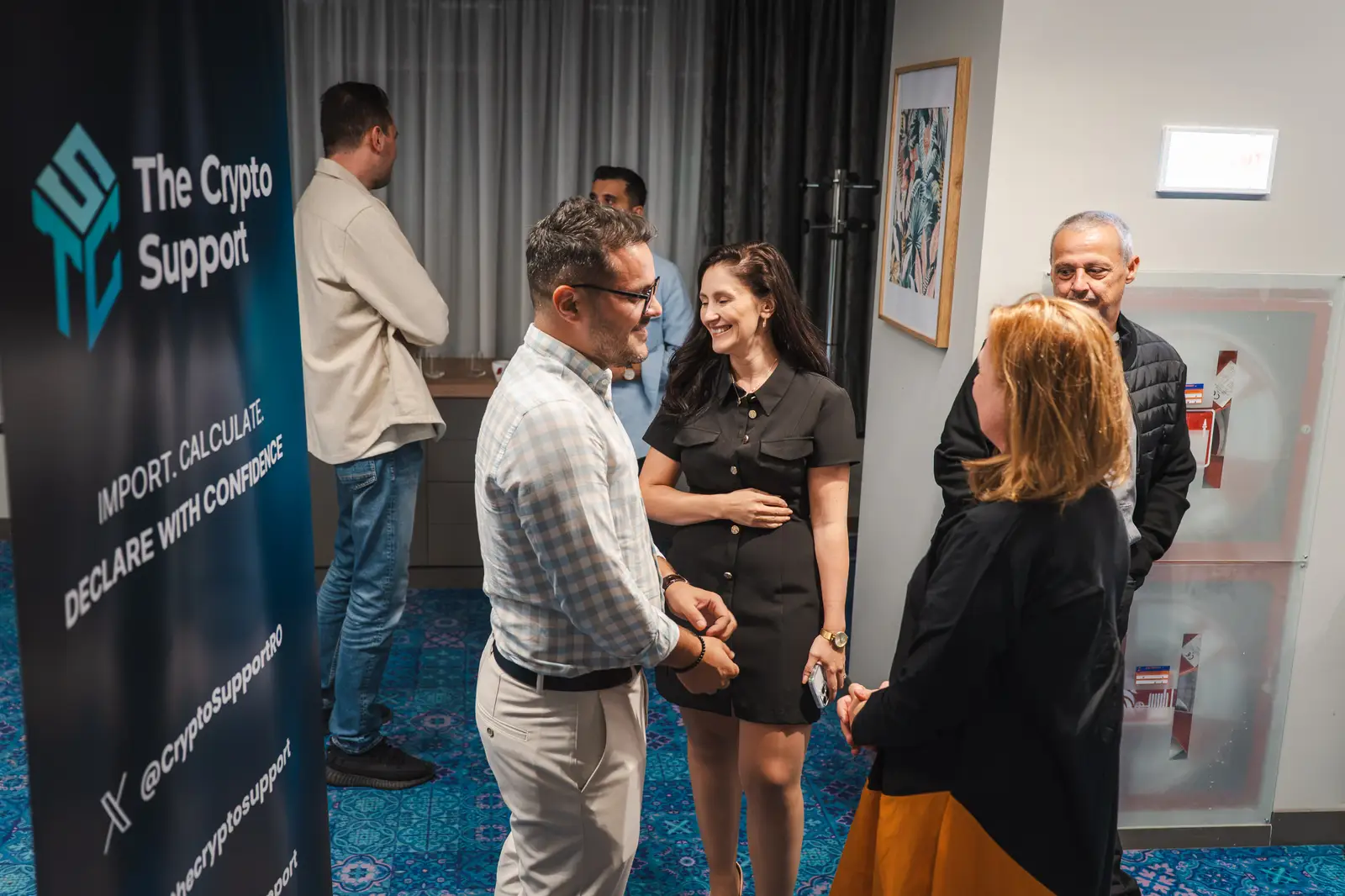 Participanți stând de vorbă lângă bannerul The Crypto Support, la Mercure Sibiu Arsenal.